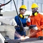 engineer cooperation male and female technician maintenance control relay robot arm system welding with tablet laptop to control quality operate process work heavy industry 4.0 manufacturing factory