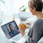 Woman using laptop and having video call with her doctor while sitting at home.